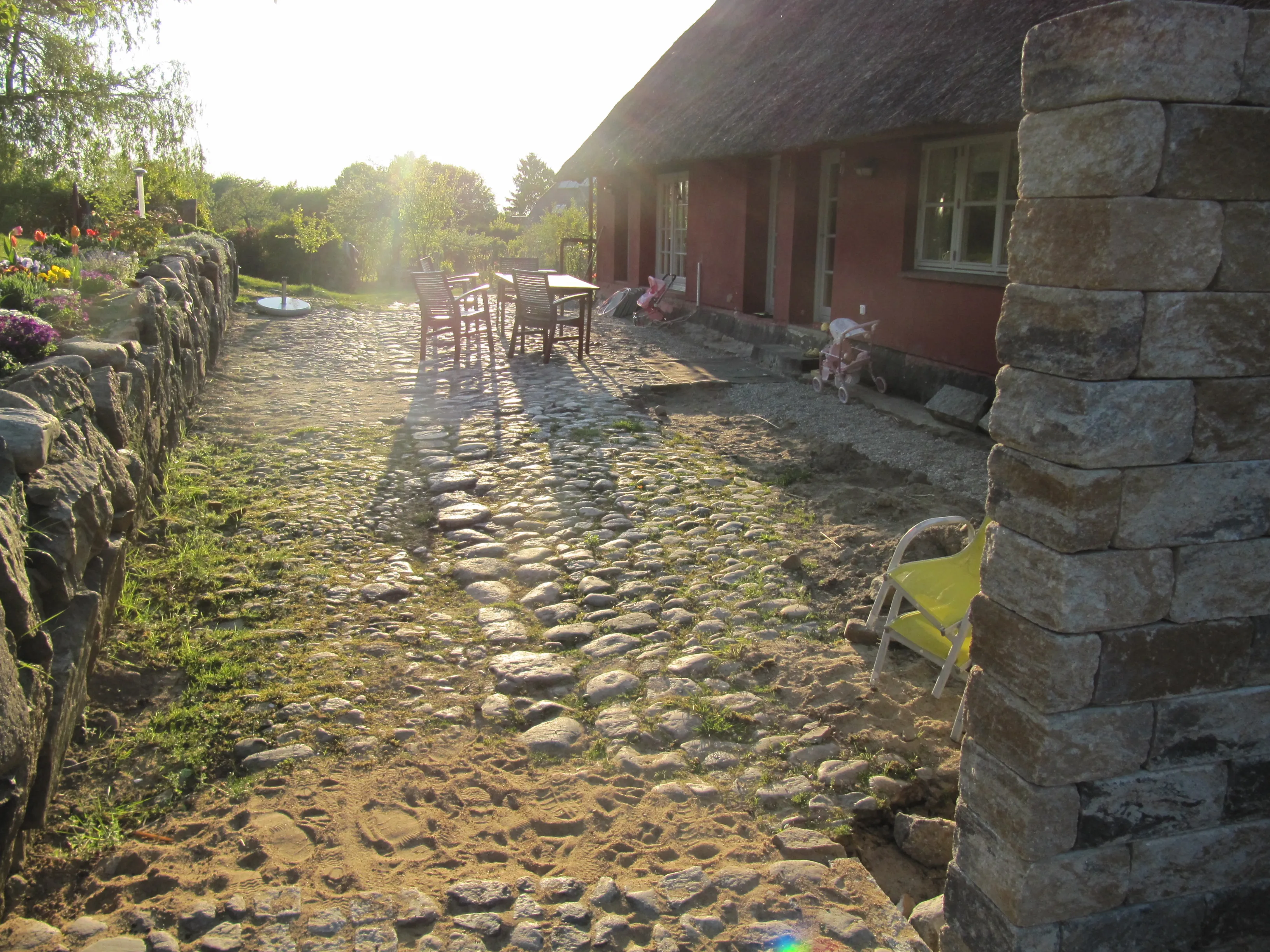 Natursteinweg entlang eines Hauses mit Trockenmauer im warmen Abendlicht